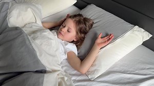 Little girl sleeping peacefully in a large adult bed. Concept of childhood vulnerability, safety and innocence in a grown-up world. High quality 4k footage