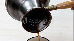 coffee pouring from stainless steel turkish coffee pot in cup,close up 4k.coffee lovers,americano espresso.roasted beans,dark arabica natural coffee,homemade tasty delicious drink