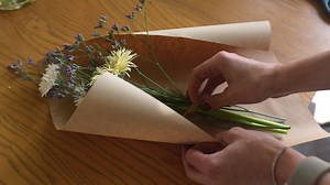 Florist wraps flower bouquet in brown paper and twine