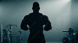 Close-up view of a bodybuilder shirtless man showing his back muscles on camera. Shot in slow-motion. Strong athletic man showing muscular body 4k video