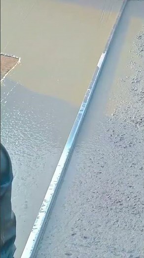 smoothing out wet concrete using a long metal straight edge tool on a construction site carefully