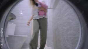 Woman is putting dirty laundry, clothes into the washing machine in the bathroom - point of view, inside pov shot. Housekeeping, technology and housework concept