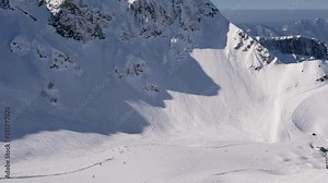 Skiers And Snowboarders Skiing Down Snowy Ski Track In Rocky Mountains In Winter