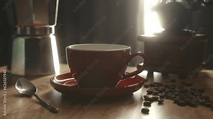 Red cup of evaporating coffee on the table with roasted bean, steaming cup of coffee or tea. Coffee cup and beans. Motion coffee pour. 4K