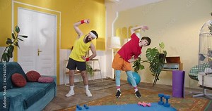 Full length view of the two young caucasian men wearing sport outfit standing at the floor and exercising at the morning at the flat. Spor, gym, motion and healthy lifestyle concept