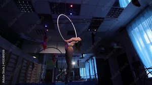 Aerial acrobat woman on circus stage. tricks hoop on a blue background