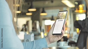 young woman sits at the cafe' uses smart phone app to search job online,back view of female using smartphone looking for occupation,vacancy on internet search engine work app