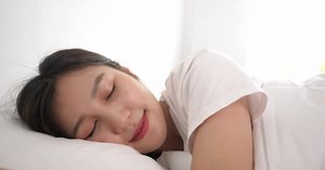 Attractive Woman Sleeping Peacefully in White Bedroom