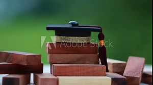 Graduation celebrating cap on wooden square blocks tower. Blank space for letter e.g education, study plan, graduate, etc. Ideas for Successive business abroad international Educational