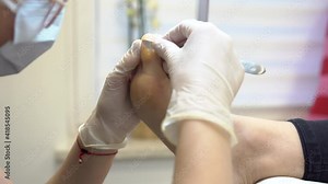 Pedicurist uses scalpel to remove dead skin from woman foot. A woman cutting toe skin with scalpel. Foot care treatment in salon. Pedicure concept. Process of professional pedicure.