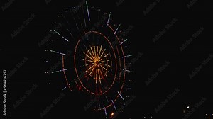 Ferris wheel in the night city with brightly colored illumination. The devil's wheel spins and glows in the night