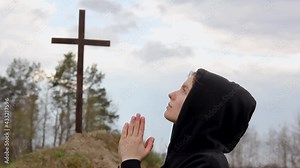 The girl prays at the cross. Carry the cross. Worshiping God before the cross. Man believes in God. Hope in God