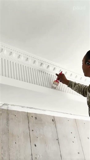Painting the intricate decorative ceiling moldings with a fine brush to enhance the room elegance