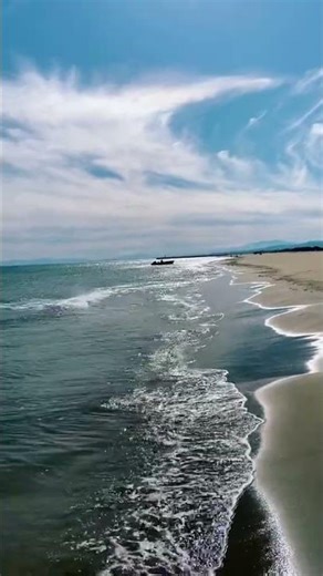 This video shows a scenic view of a beach with a boat on the water. #pierphotography