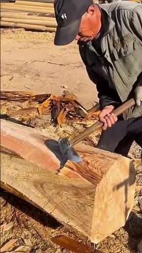 Lumbering Worker Shaping or Debarking a Large Wooden Log with an Axe
