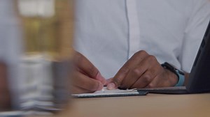 Hands of mature man, writing, pressing paper, man-s face watching focused on hands, turning head to light of laptop - laptop not shown