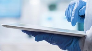 Close up shot of scientist in gloves typing on a tablet PC screen in laboratory