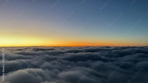 Sunset view from a jet cockpit overflying clouds with an orange horizon. pilot point of view.