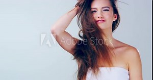 Passionate about haircare. 4k video footage of a beautiful young woman playing with her hair in the studio.