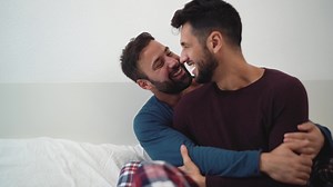 two men are hugging while sitting on a bed