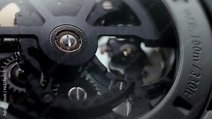 Mechanical watches with gears and cogs. Watch or clock mechanism.Mechanical skeleton watch. Clockwork details and parts.Clock gears running with dramatic flickering light.Open balance extreme closeup