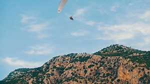 Paraglider cruising through the sky over a mountain - Free Stock Video
