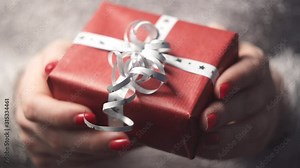 Close-up of woman's hands holding a box with a gift in her hands, the camera enters the focus area. Slider shot.