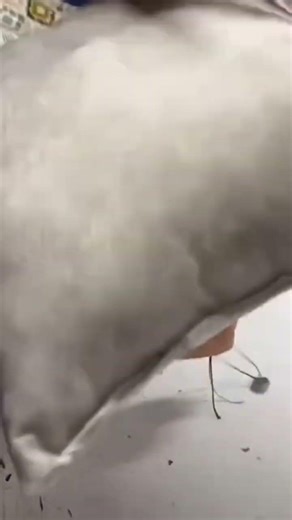 This is the process of making a pillow by a worker using a needle and thread