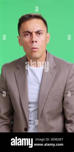 Frightened man expressing panic and anxiety with his hands, feeling scared against a green background