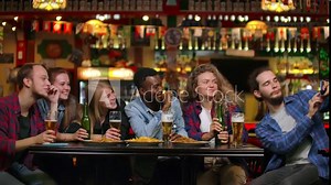 Friends take pictures on the phone at the bar, make a shared photo on the phone. Party with friends at the bar with beer
