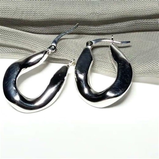 Hoop earrings made in shimmering sterling silver with a fancy twisted design to them
