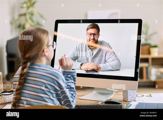 Caucasian girl sitting at desk participating in online video call with Caucasian young adult man displayed on computer monitor, both engaging in remote learning or virtual meeting Stock Photo - Alamy