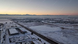 Aerial view of Front Range mountains looking towards Boulder and Longmont, CO from I-25 on a winter evening . Drone video of roads and suburbs in North Colorado with snow on ground.