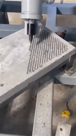 triangle pattern onto grey stone slab using automatic cnc machine tool inside industrial factory