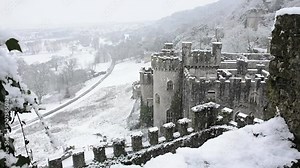 Gwrych castle Abergele, Welsh European castle in gently falling snow with Abergele town in the distance and road leading to it.