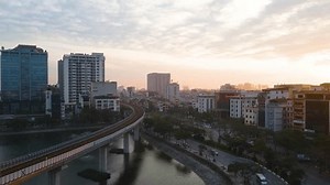 Hanoi, Vietnam - Jan 20, 2025: An aerial view of Hanoi at sunrise. A network of roads and elevated railway, with high-rise buildings and residential areas stretching towards the horizon.