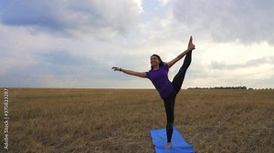 Young woman is practicing yoga outdoor on the grass at dawn. Stretching exercise on field with nature view. Calmness and mindfulness, meditation, flexible body