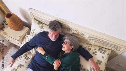 Mature couple talking and cuddling in bed in the morning