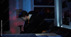 Angry gamer breaking a keyboard on the table in his room. Young guy has a tantrum from a loss in a video game. gamer freaks out and breaks the keyboard.