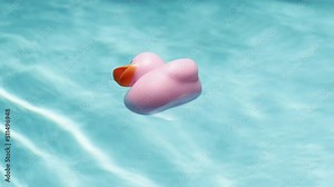 Close-up of a pink rubber duck floating in a pool as sun light reflects off ripples in water.