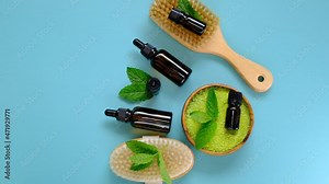 Essential mint oil and salt with mint extract, body brushes and fresh mint sprigs on bright blue background.Beauty and aromatherapy.Glass bottles with mint oil and sea green salt.