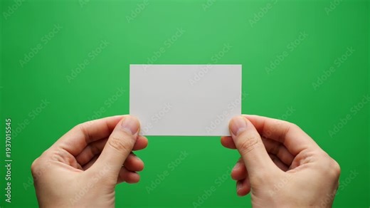 Hands hold a blank white business card against a green screen background, ideal for contact information and networking.