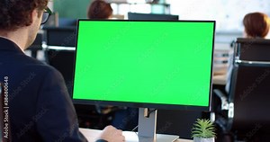 Close up of monitor in office. Green screen. Employee working at computer sitting at desk. View from back.