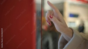 Girl using touch terminal makes a quick order through the self-service. Woman choosing dessert via self-service machine at fast food restaurant. Person swipes the screen making an order.
