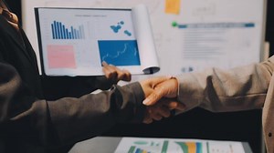 Download Two business people shaking hands over a piece of paper for free