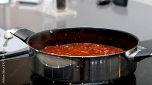 Homemade bolognese sauce gently cooking in pot on induction hob