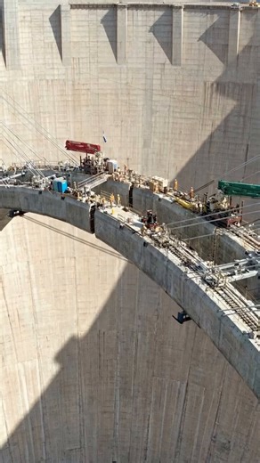 Incredible Construction of Mike O'Callaghan Pat Tillman Memorial Bridge Against Massive Hoover Dam FaceWitness the absolutely breathtaking aerial construction footage of the Mike O'Callaghan Pat Tillman Memorial Bridge being built directly in front of the towering face of the iconic Hoover Dam, showing the incredible cable stay construction method used to advance the massive concrete arch spans out from both sides simultaneously over the deep Black Canyon gorge, with construction equipment, cran