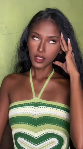 Woman Posing in Crocheted Halter Top Against Green Wall