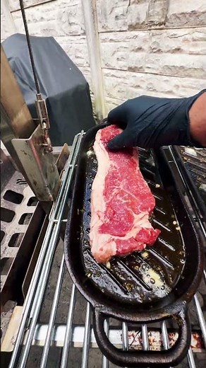 Cooking a New York strip steak in a cast-iron skillet.