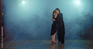 Beautiful woman dancing romantic tango with elegant man in black suit. Professional dancers dance in the hall with smoke. 4k, ProRes Stock Video